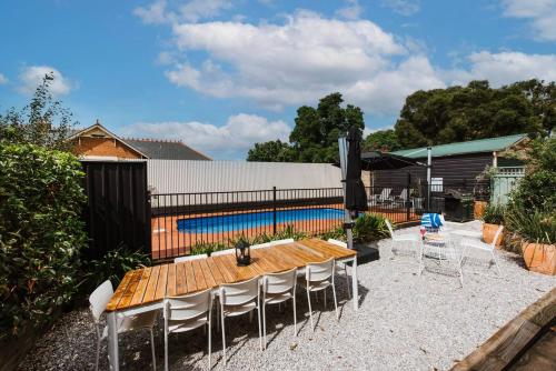 a patio with a wooden table and chairs and a pool at Mortimer Cottage - A Pool Oasis in Heart of Mudgee in Mudgee