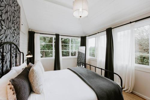 1 dormitorio con cama blanca y ventanas en Mortimer Cottage - A Pool Oasis in Heart of Mudgee, en Mudgee