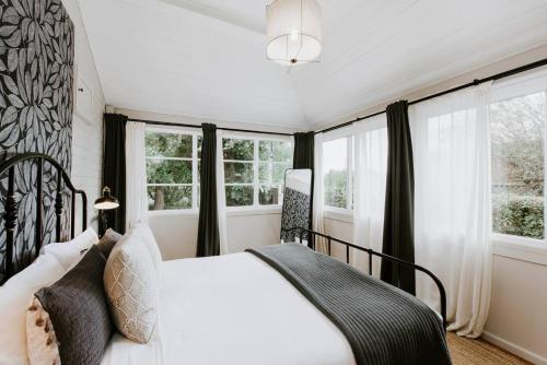 a bedroom with a white bed and windows at Mortimer Cottage - A Pool Oasis in Heart of Mudgee in Mudgee