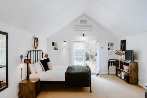 a white bedroom with a bed and a window at The Annex - A Cosy Couples Retreat in Heart of Town in Mudgee