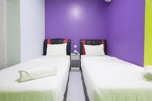 two beds in a room with purple walls at SY JERANTUT HOTEL in Jerantut