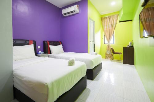 two beds in a room with purple and green walls at SY JERANTUT HOTEL in Jerantut
