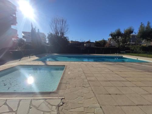une piscine vide au soleil en arrière-plan dans l'établissement Appartement avec Piscine & Tennis, Terrasse ensoleillée, Garage privé - Antibes - FR-1-252-126, à Antibes