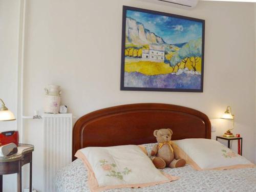 un ours en peluche assis sur un lit sous un tableau dans l'établissement Appartement avec Piscine & Tennis, Terrasse ensoleillée, Garage privé - Antibes - FR-1-252-126, à Antibes