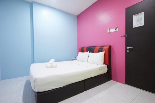 a bed in a room with a pink and blue wall at SY JERANTUT HOTEL in Jerantut
