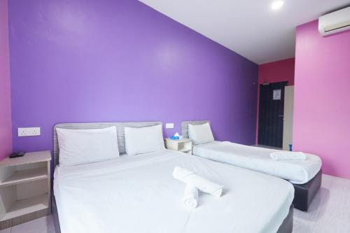 two beds in a room with a purple wall at SY JERANTUT HOTEL in Jerantut