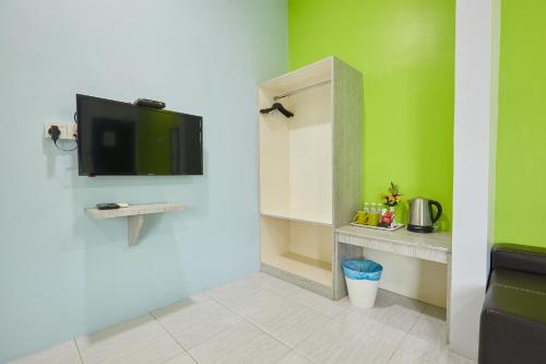 a room with a tv on a wall with green walls at SY JERANTUT HOTEL in Jerantut