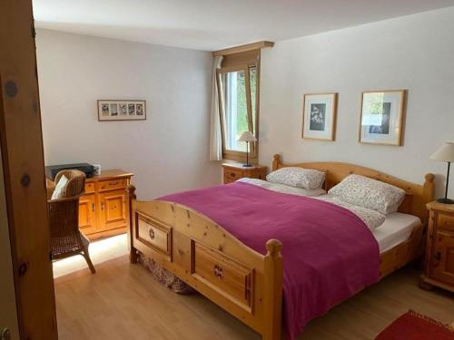 a bedroom with a wooden bed with a purple blanket at Ferienwohnung mit Aussicht bei Golfplatz Buna Vista in Schleuis