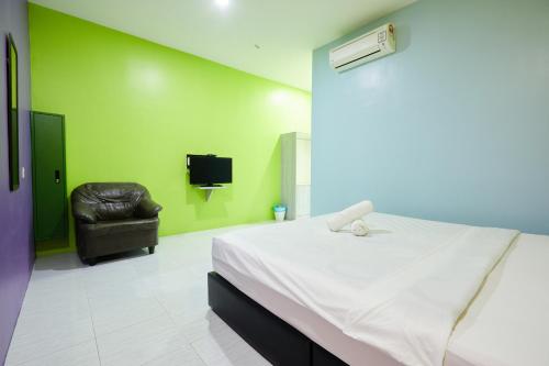 a bedroom with a bed and a leather chair at SY JERANTUT HOTEL in Jerantut