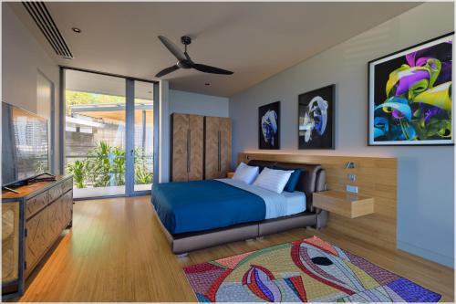 a bedroom with a blue bed and a television at The Cube Ocean View Pool Villa Kalim in Patong Beach
