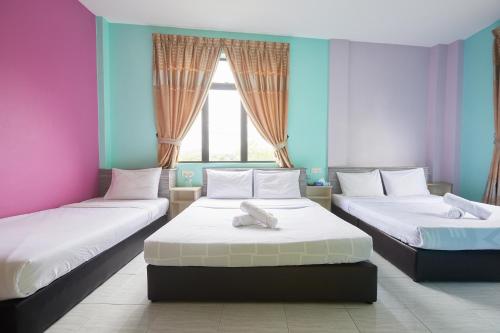 two beds in a room with pink and blue at SY JERANTUT HOTEL in Jerantut