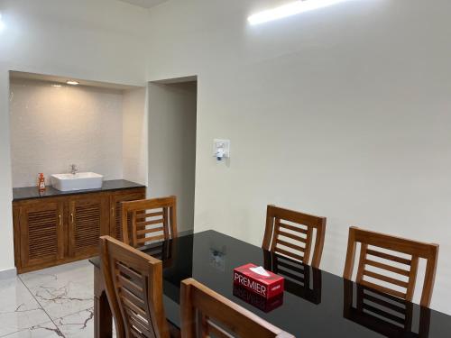 La salle de bains est pourvue d'un lavabo, d'une table et de chaises. dans l'établissement Solomon Apartments,Alappuzha beach., à Alappuzha