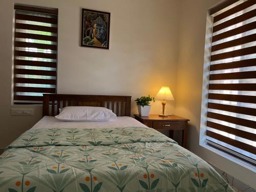 a bedroom with a bed and a table with a lamp at Solomon Apartments,Alappuzha beach. in Alleppey