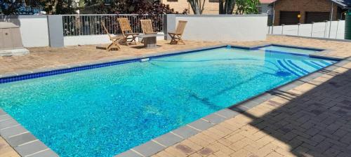 a blue swimming pool with two chairs and a table at The Wishing Well Guest House Self-Catering in Port Edward