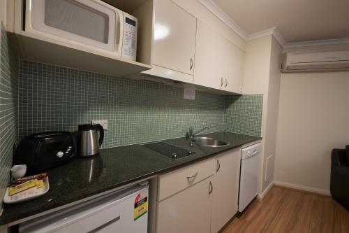 a kitchen with a sink and a microwave at Napoleon On Kent in Sydney