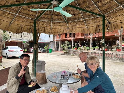 a group of people sitting at a table under an umbrella at VuLinh Family -Homestay in Yên Bình