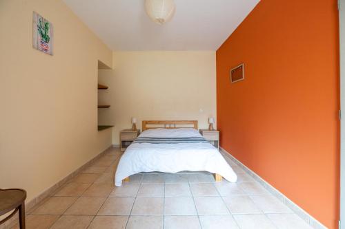 ein Schlafzimmer mit einem Bett und einer orangefarbenen Wand in der Unterkunft L'Arbre Rouge & L'Arbre Vert in Jonzac