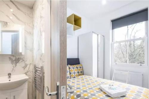 a bathroom with a bed and a sink and a mirror at Boutique Modern Hotel Room For Two Near Tube And Bus Stations in London