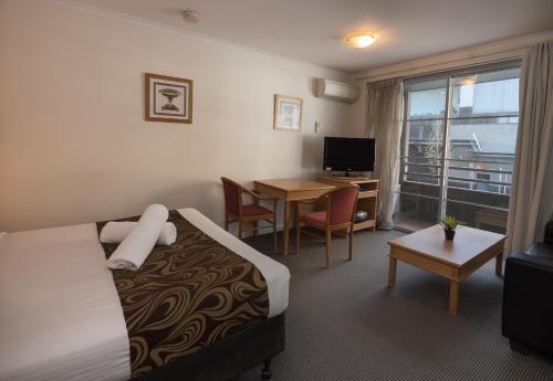 a hotel room with a bed and a table and a desk at Napoleon On Kent in Sydney