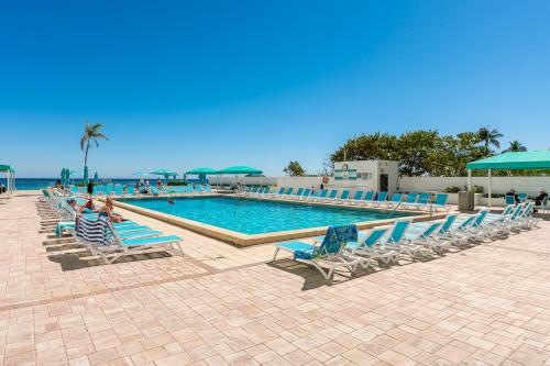 a swimming pool with lounge chairs and the ocean at AMAZING 2BR 2BA NEWLY RENO BEACHFRONT APT W/BEACH VIEW in Hollywood