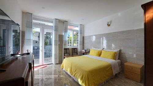 een slaapkamer met een geel bed en een balkon bij Ánh Dương House in Da Lat