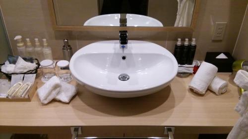 a sink in a bathroom with a mirror and towels at Rembrandt Hotel Tokyo-Machida in Machida
