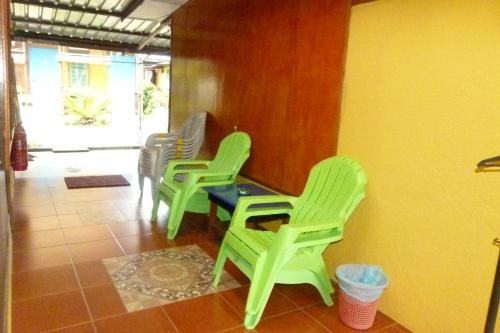 four green chairs and a table in a room at Cheers Garden Chalet in Kampung Tekek
