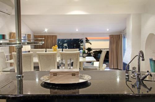 a kitchen counter with a sink and a dining room at Rontree Reflections in Cape Town