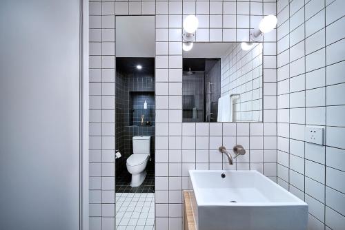 a white tiled bathroom with a sink and a toilet at base-SUHE Serviced Apartment in Shanghai