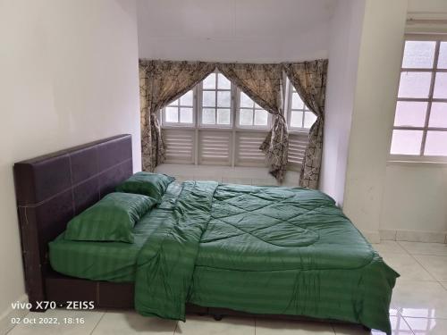 a bedroom with a green bed with a window at Bani's Penthouse (Homestay Cameron Highlands) in Tanah Rata