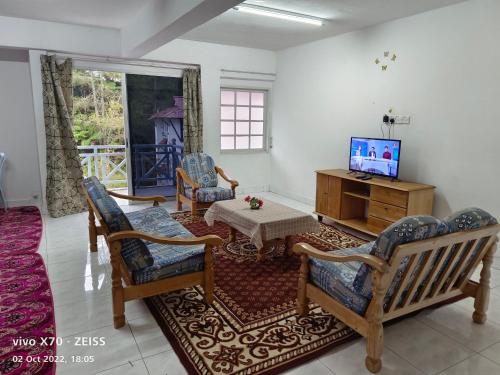 sala de estar con TV, mesa y sillas en Bani's Penthouse (Homestay Cameron Highlands), en Tanah Rata