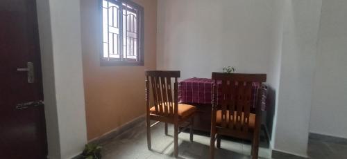 ティルチラーパッリにあるUthamar Illamの窓のある客室で、椅子2脚とテーブル1台が備わります。
