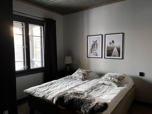 a bed in a bedroom with two pictures on the wall at Porthos Ski-in Lodge with private hot tub and sauna in Lapland in Pyhätunturi