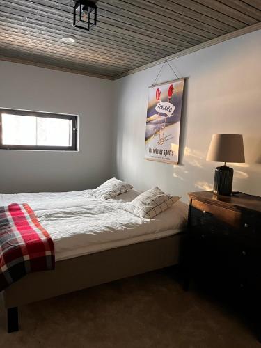 a bedroom with a bed and a table with a lamp at Porthos Ski-in Lodge with private hot tub and sauna in Lapland in Pyhätunturi