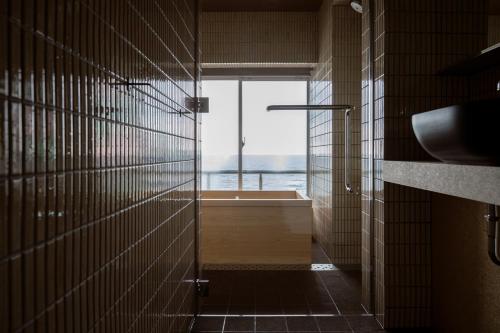 a bathroom with a bath tub and a window at Kameya Hotel in Tsuruoka