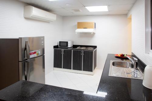 a kitchen with a sink and a refrigerator at Muscat Hills Hotel in Muscat