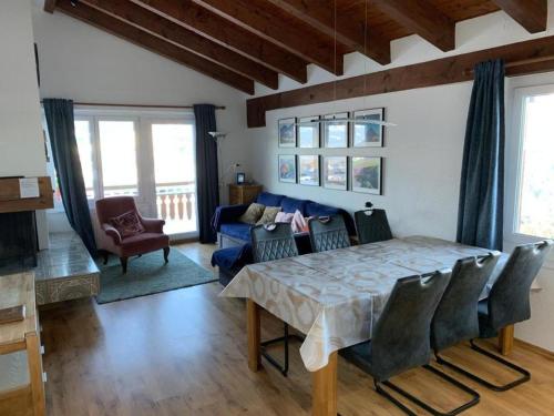 uma sala de estar com uma mesa e um sofá azul em Aparthaus Surselva, Obersaxen Surcuolm, direkt an der Skipiste em Surcuolm