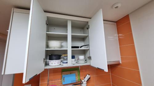 una cocina con armarios blancos y azulejos de color naranja en New world hwani House, en Seúl