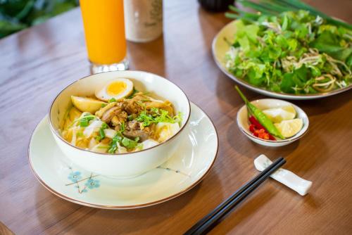 a wooden table with a bowl of food and a salad at Bonny Boutique Hotel Da Nang in Da Nang