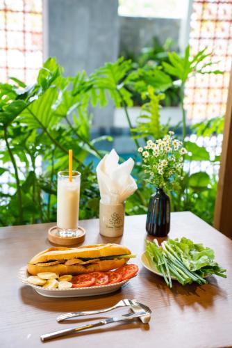 a table with a sandwich and a plate of food at Bonny Boutique Hotel Da Nang in Da Nang