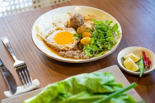 a plate of food with an egg and meatballs and greens at Bonny Boutique Hotel Da Nang in Da Nang
