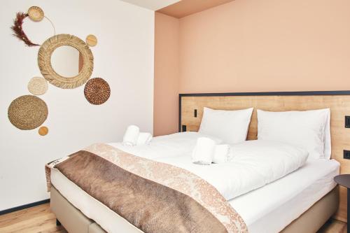 a bedroom with a bed with white sheets and a mirror at HOMEBOUND APARTMENTS Bad Goisern - contactless check-in in Bad Goisern