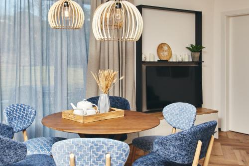 a dining room with blue chairs and a table and a tv at HOMEBOUND APARTMENTS Bad Goisern - contactless check-in in Bad Goisern