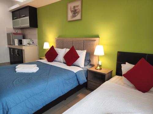 um quarto com 2 camas com almofadas vermelhas e brancas em The Viana Apartment 2 em Kota Bharu