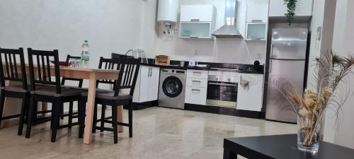 eine Küche mit einem Tisch und Stühlen sowie einem Kühlschrank in der Unterkunft Joli appartement Mohammédia in Mohammedia