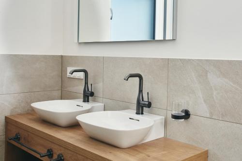 a bathroom with two white sinks and a mirror at HOMEBOUND APARTMENTS Bad Goisern - contactless check-in in Bad Goisern