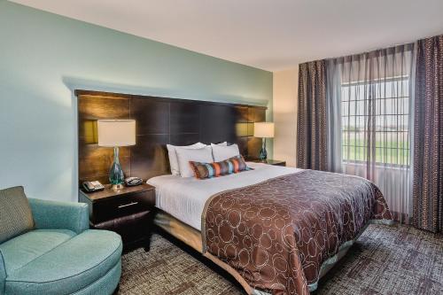 um quarto de hotel com uma cama e uma cadeira em Staybridge Suites Bismarck, an IHG Hotel em Bismarck