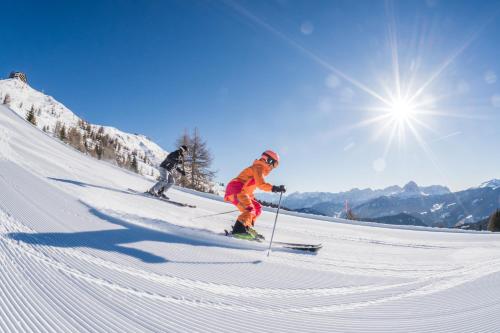 two people are skiing down a snow covered slope at Hotel Falken in Falzes