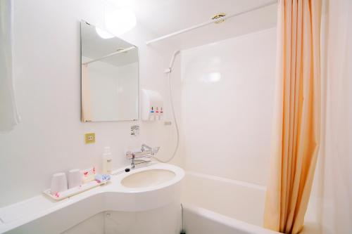 a white bathroom with a sink and a mirror at Hotel Wing International Shonan Fujisawa in Fujisawa