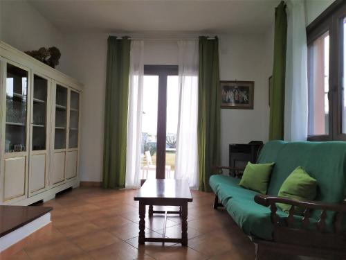 a living room with a green couch and a table at Ajò Faci a Mari in Capoterra